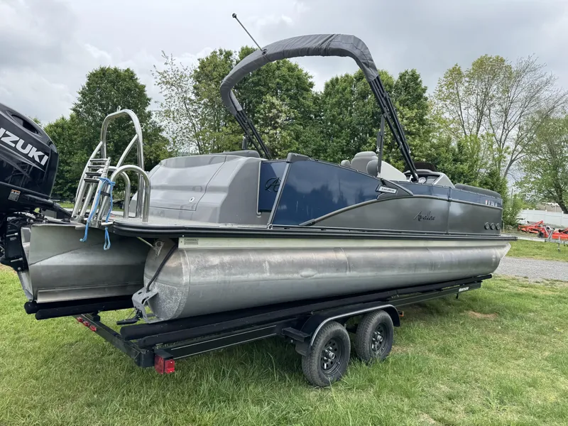 Slide: The Image of 2021 Avalon Catalina Rear J Lounger 25' pontoon boat on trailer, grassy area, overcast sky. - 10