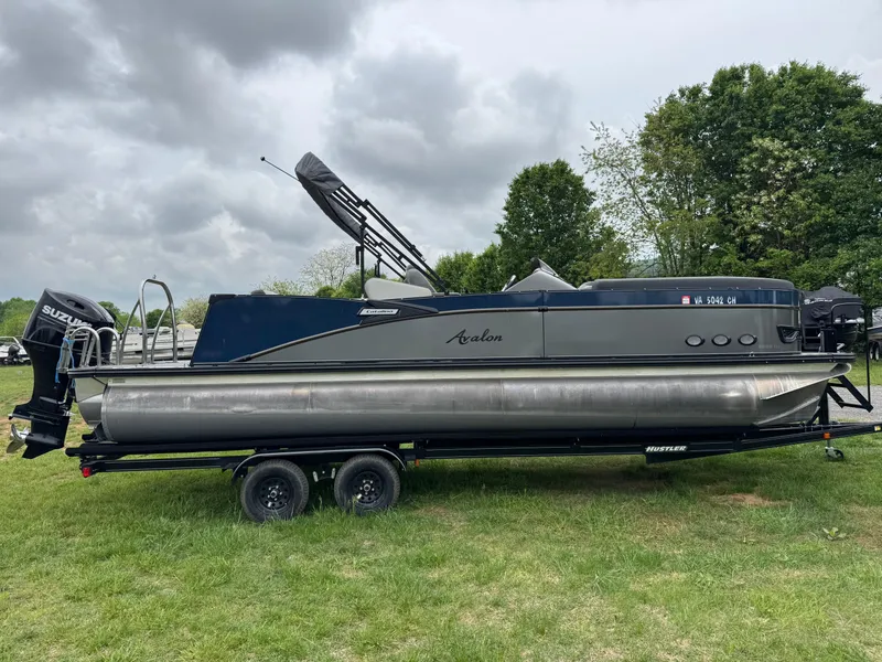 Slide: The Image of 2021 Avalon Catalina Rear J Lounger 25' pontoon boat on trailer, grassy field background. - 11