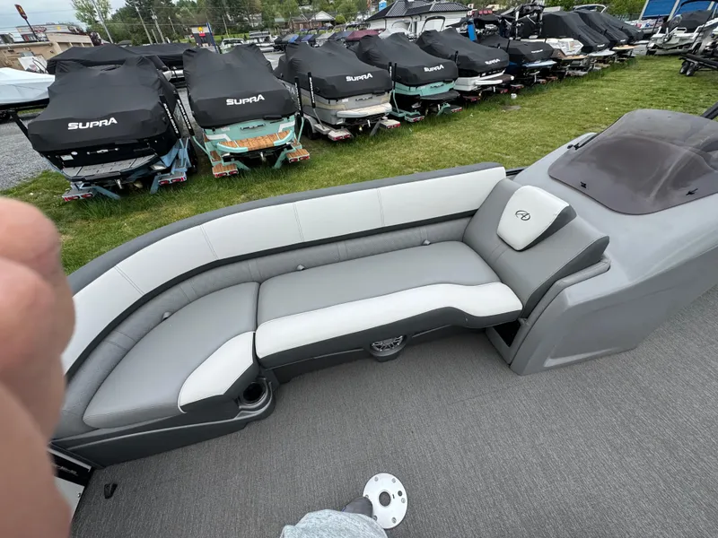 Slide: The Image of 2021 Avalon Catalina Rear J Lounger 25' boat interior with gray seating and covered boats in background. - 12