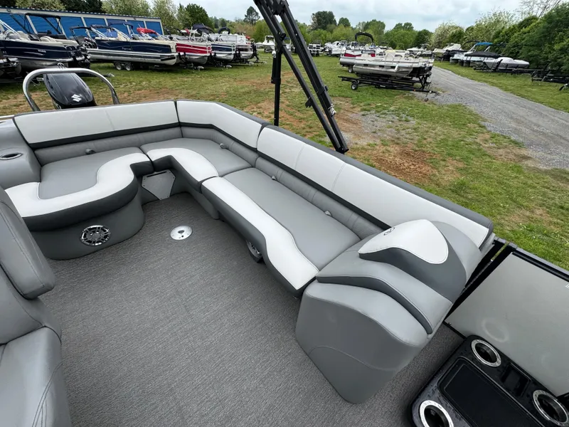 Slide: The Image of 2021 Avalon Catalina Rear J Lounger 25' interior with gray seating, parked among other boats. - 13
