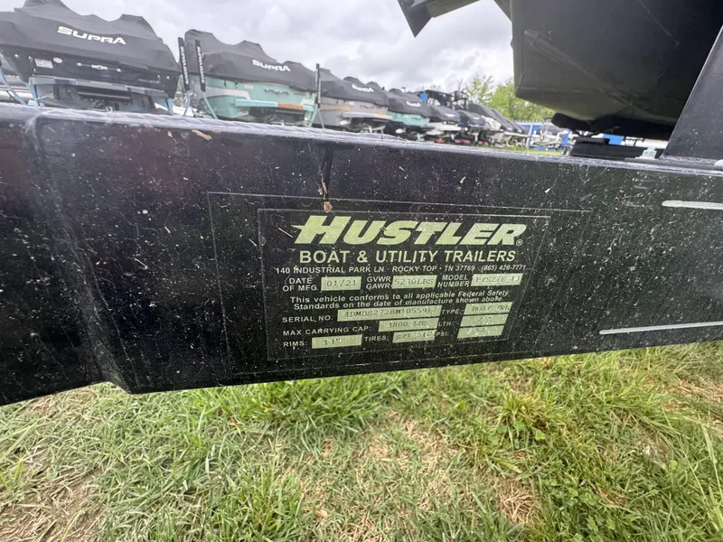 Slide: The Image of Trailer label for Hustler Boat & Utility Trailers on grass background. - 18