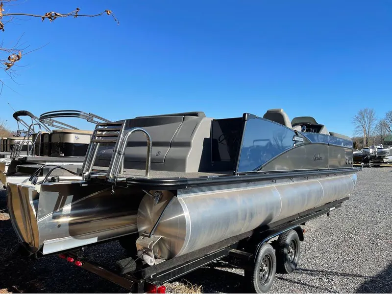 Slide: The Image of 2021 Avalon Catalina Rear J Lounger 25' pontoon boat on trailer, under clear blue sky. - 24