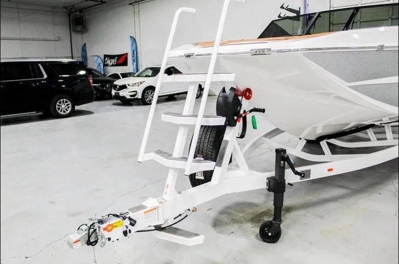 Slide: The Image of 2025 Tigé 22RZX boat on trailer in showroom with cars in background. - 33