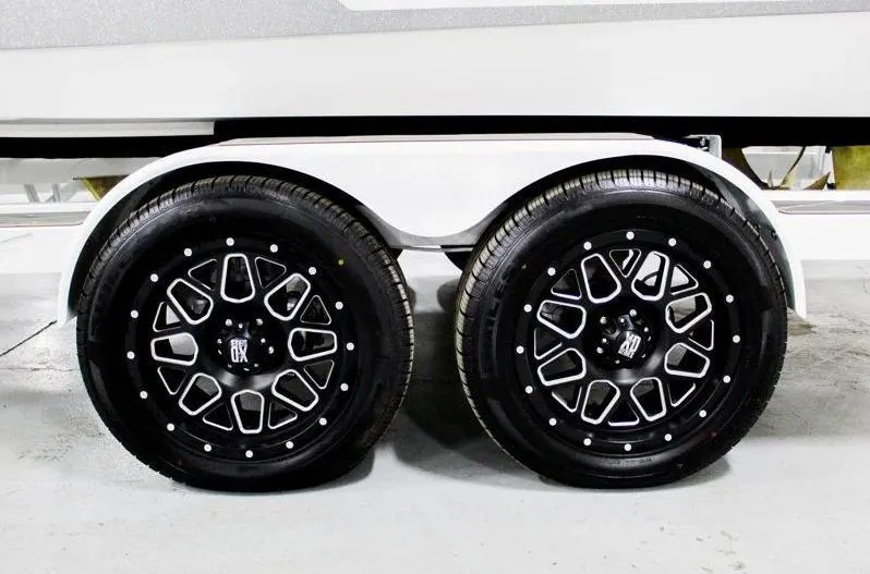 Slide: The Image of 2025 Tigé 22RZX trailer wheels with stylish black rims in a garage setting. - 34