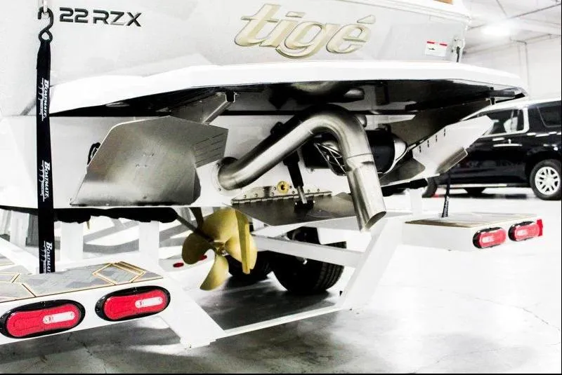 Slide: The Image of 2025 Tigé 22RZX boat rear view, showcasing propeller and exhaust system in a garage setting. - 35