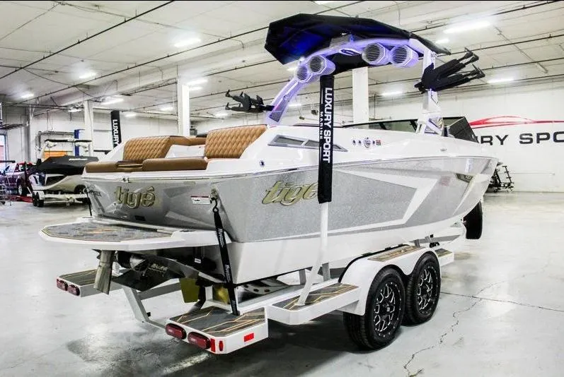 Slide: The Image of 2025 Tigé 22RZX boat on trailer in showroom, featuring sleek design and modern amenities. - 6