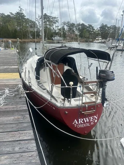 The Image of 1979 Bristol 299 sailboat docked, featuring a red hull and black canopy, named "Arwen." - 0