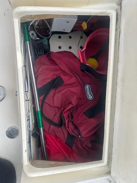 Slide: The Image of Storage compartment in a 1979 Bristol 299 boat with red bag and cleaning tools. - 16