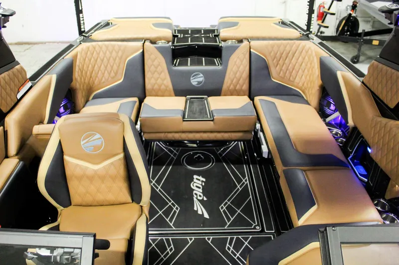Slide: The Image of 2025 Tigé 22RZX boat interior with luxurious tan and gray seating, ambient lighting. - 12