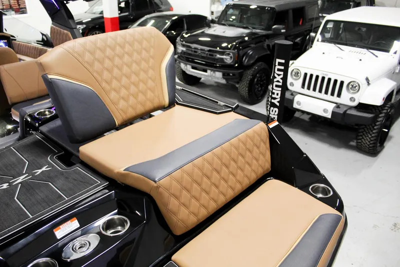 Slide: The Image of 2025 Tigé 22RZX boat interior with luxury seating, parked near SUVs in a showroom. - 26