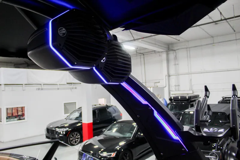 Slide: The Image of 2025 Tigé 22RZX boat interior with illuminated speakers and sleek design in a showroom. - 27