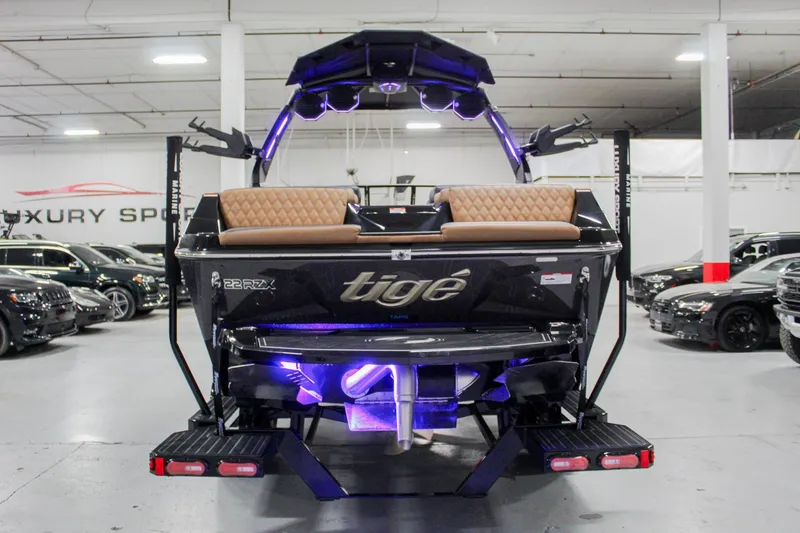 Slide: The Image of 2025 Tigé 22RZX boat in showroom, rear view with illuminated interior and sleek design. - 3