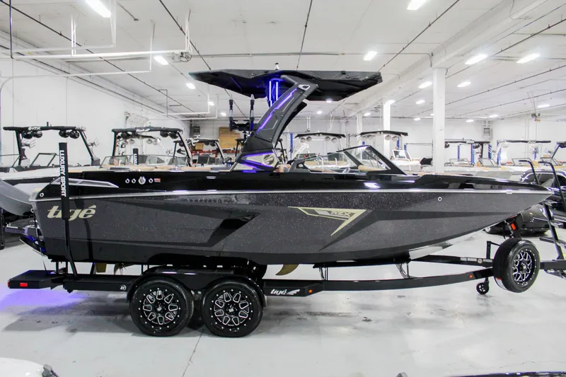 Slide: The Image of 2025 Tigé 22RZX boat in showroom, sleek black design, on trailer. - 5