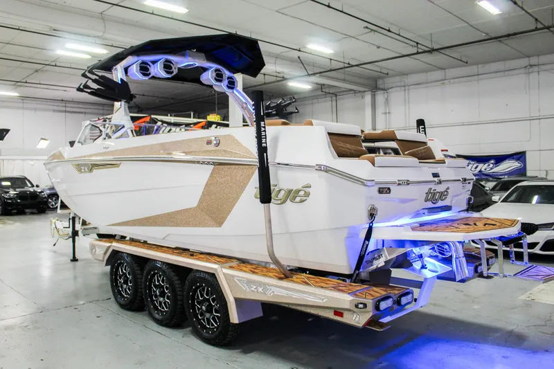 Slide: The Image of 2025 Tigé Ultré 25ZX boat in showroom, featuring sleek design and vibrant blue lighting. - 2