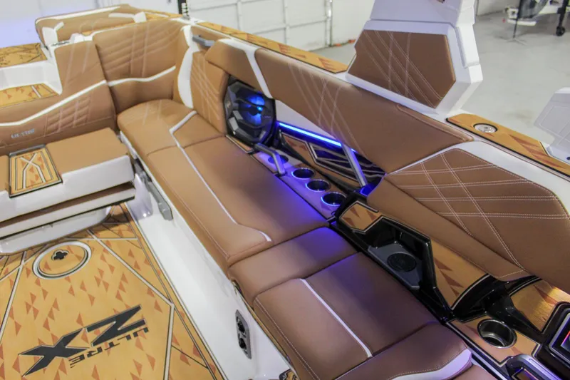 Slide: The Image of 2025 Tigé Ultré 25ZX boat interior with brown seating and blue LED lighting. - 25