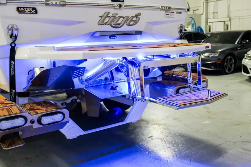 Slide: The Image of 2025 Tigé Ultré 25ZX boat with illuminated swim platform in a garage setting. - 43