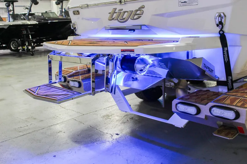 Slide: The Image of 2025 Tigé Ultré 25ZX boat with illuminated swim platform and sleek design in a showroom. - 44
