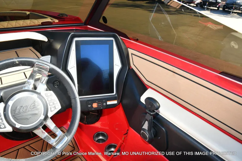 Slide: The Image of 2022 Tigé 24RZX boat dashboard with touchscreen and steering wheel, featuring red and beige interior. - 24