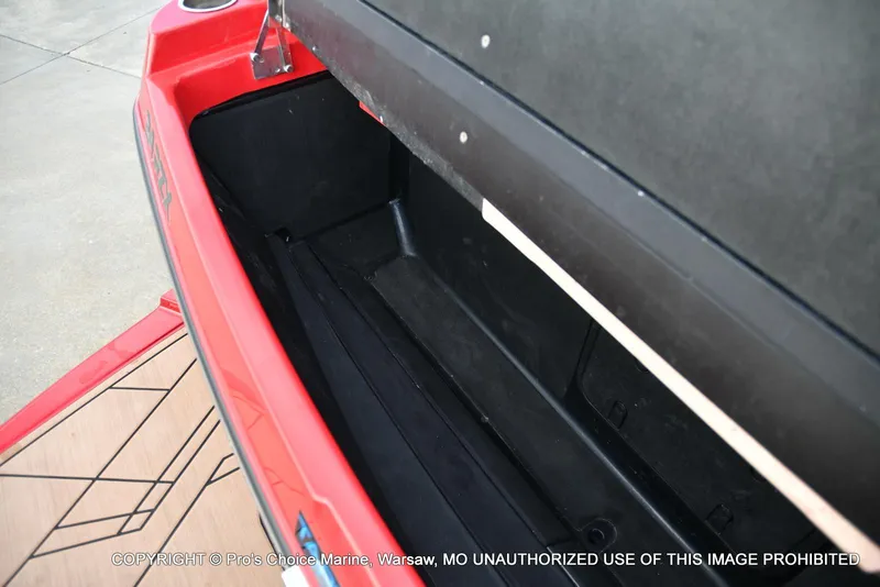 Slide: The Image of Open storage compartment in 2022 Tigé 24RZX boat, featuring red exterior and black interior. - 44