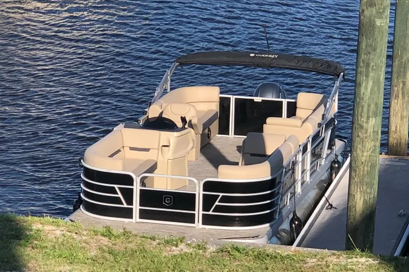 Slide: The Image of 2023 Sweetwater SW 2286 SB pontoon boat docked by the water. - 2