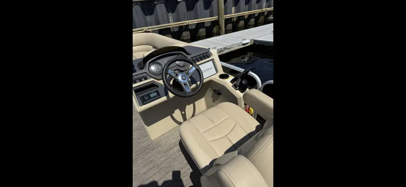 Slide: The Image of 2023 Sweetwater SW 2286 SB boat interior with steering wheel and beige seating. - 7