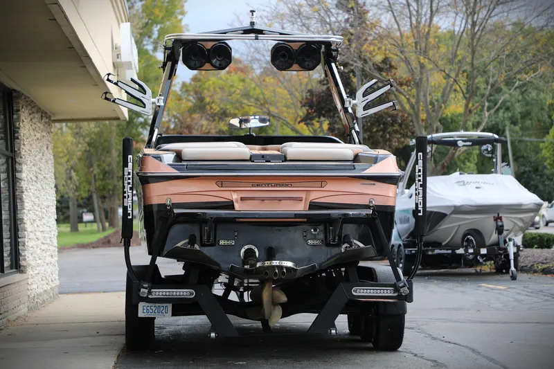 Slide: The Image of 2021 Centurion Ri245 boat, rear view, parked outdoors with trees in the background. - 3