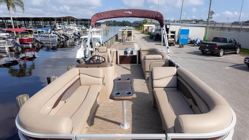 Slide: The Image of 2024 Bennington 20SSR pontoon boat with spacious seating, docked near a marina. - 3