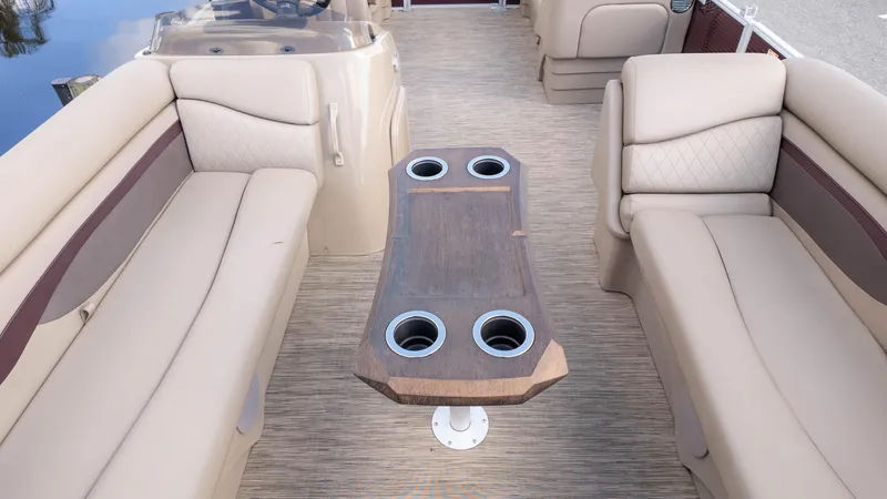 Slide: The Image of 2024 Bennington 20SSR pontoon boat interior with beige seating and central table. - 9