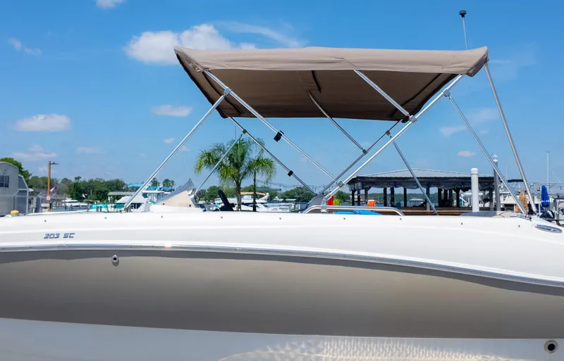 Slide: The Image of 2017 NauticStar 203 SC boat with canopy, docked under clear blue sky. - 30