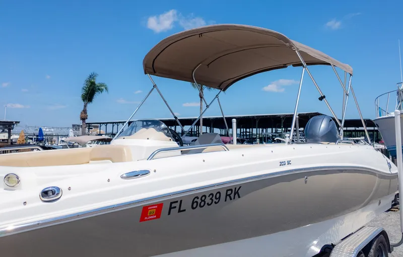 Slide: The Image of 2017 NauticStar 203 SC boat with canopy, docked in marina under clear blue sky. - 31