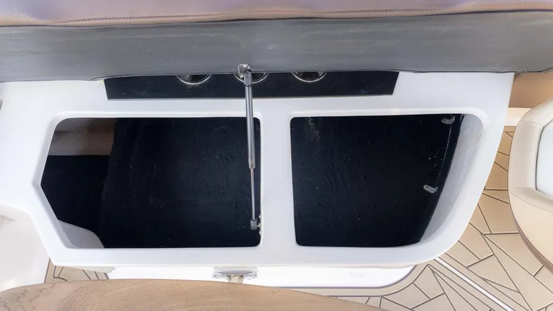 Slide: The Image of Open storage compartment on a 2015 Regal 2500 boat, featuring dual cup holders. - 16