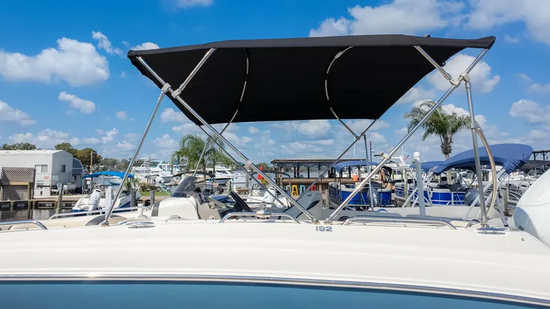 Slide: The Image of 2021 Stingray 192SC boat with canopy in marina, clear sky background. - 23