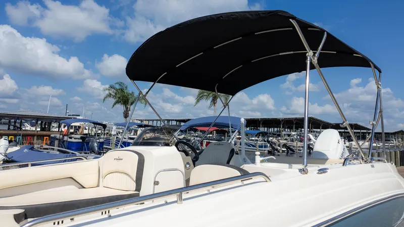 Slide: The Image of 2021 Stingray 192SC boat with canopy docked under a blue sky. - 24