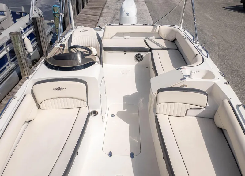 Slide: The Image of 2021 Stingray 192SC boat interior with spacious seating and sleek design at a dock. - 7