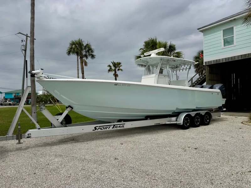Slide: The Image of 2023 Contender 35ST boat on Sport Trail trailer, parked near palm trees and a house. - 1