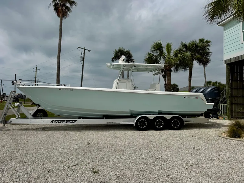 Slide: The Image of 2023 Contender 35ST boat on trailer, parked outdoors with palm trees in background. - 2