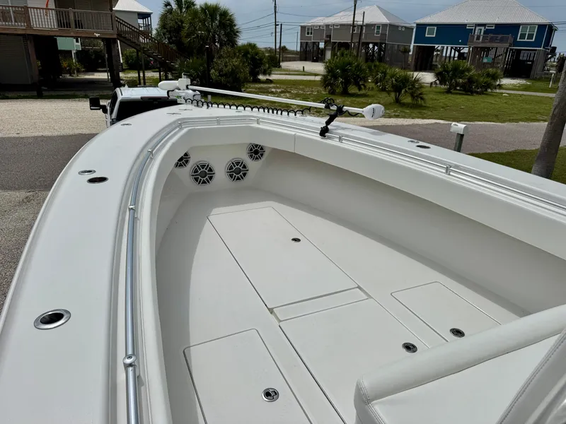 Slide: The Image of 2023 Contender 35ST boat deck with storage compartments and speakers, docked near coastal homes. - 23