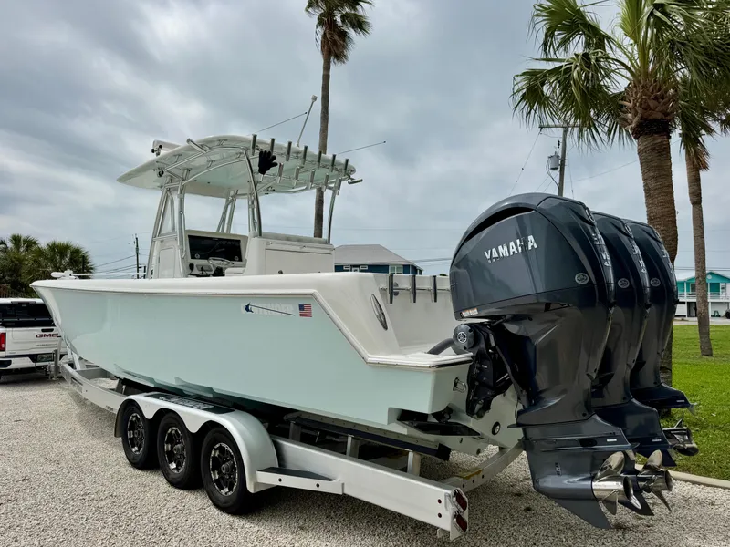 Slide: The Image of 2023 Contender 35ST boat on trailer with triple Yamaha engines, parked near palm trees. - 3