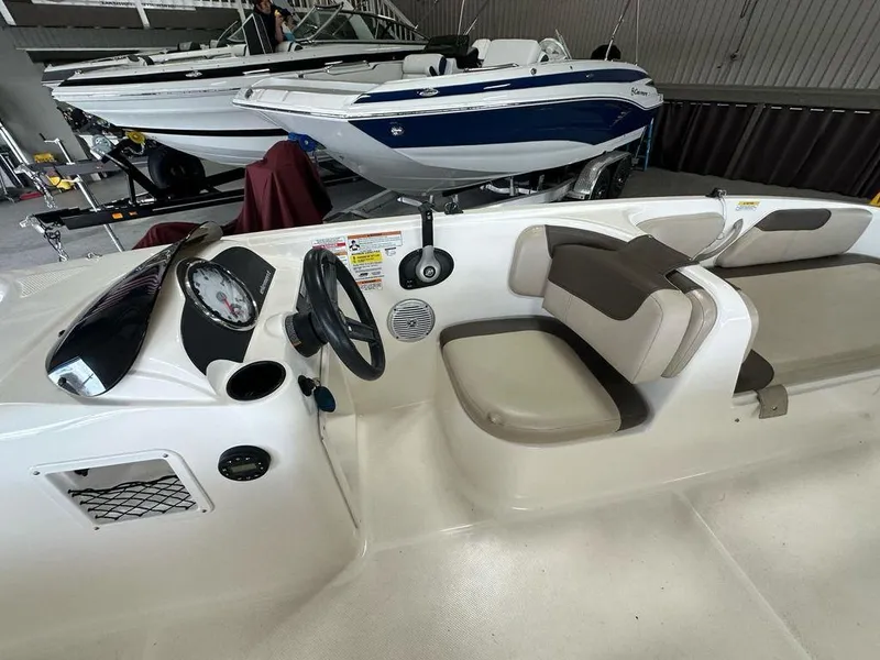 Slide: The Image of 2017 Bayliner Element 18 boat interior with steering wheel and seating in a showroom. - 9