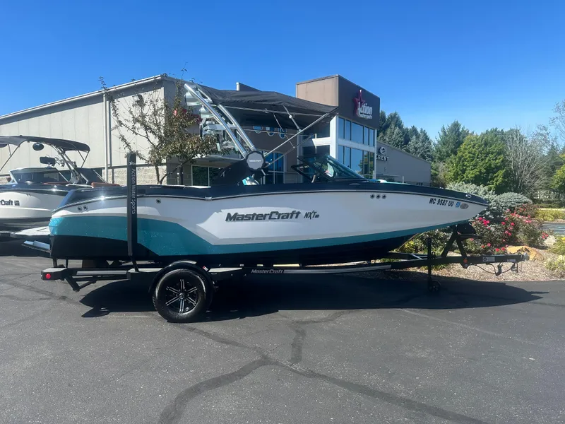 Slide: The Image of 2022 MasterCraft NXT20 boat on trailer, parked outdoors near a building. - 1