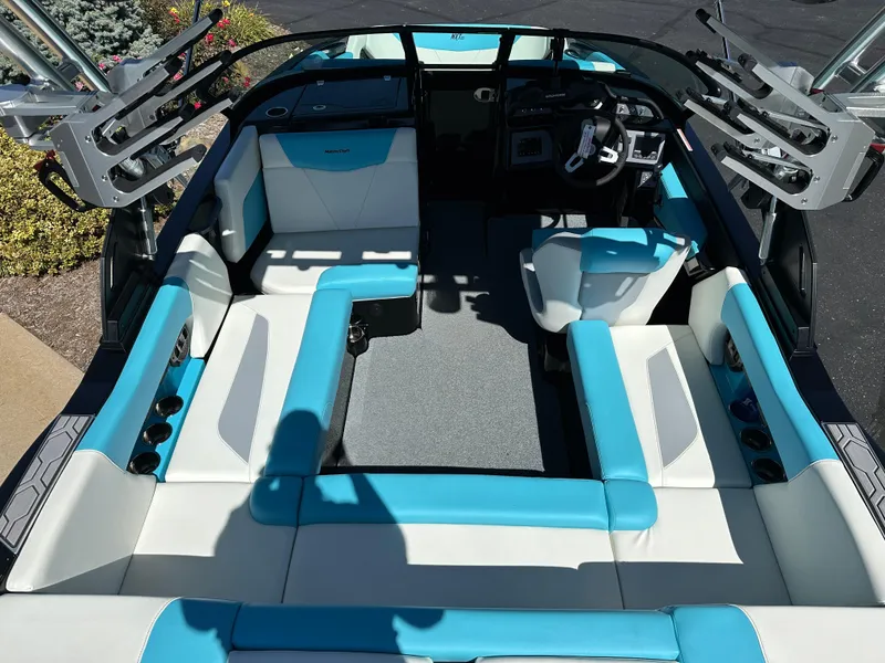 Slide: The Image of 2022 MasterCraft NXT20 boat interior with blue and white seating, steering wheel, and cup holders. - 10
