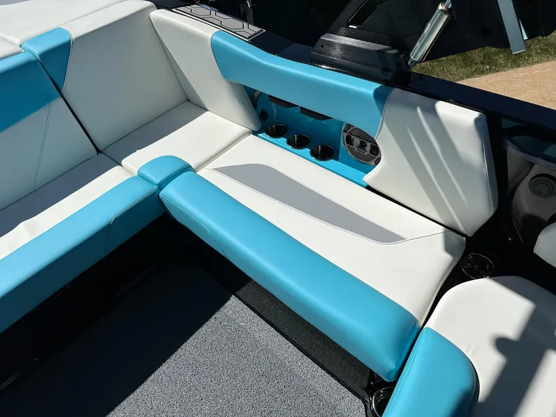 Slide: The Image of 2022 MasterCraft NXT20 boat interior with blue and white seating, cup holders, and speaker. - 14