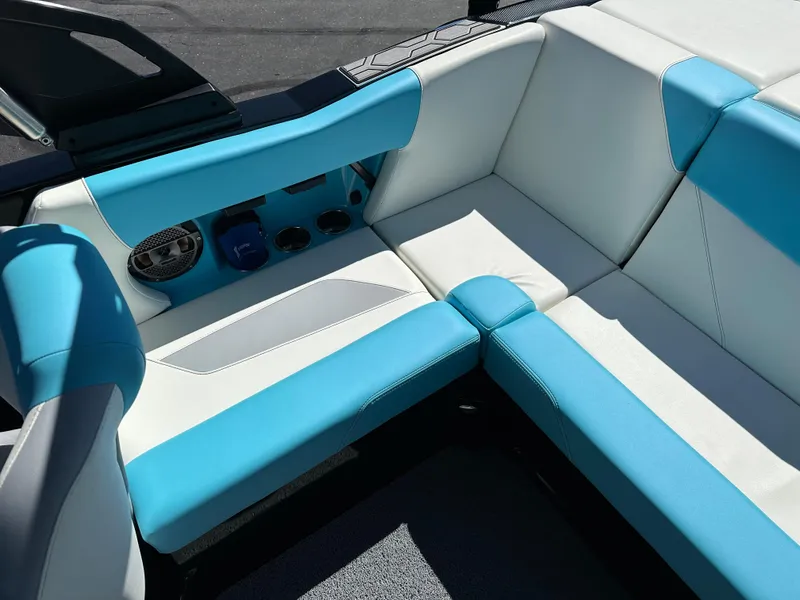 Slide: The Image of 2022 MasterCraft NXT20 boat interior with blue and white seating, cup holders, and speaker. - 16