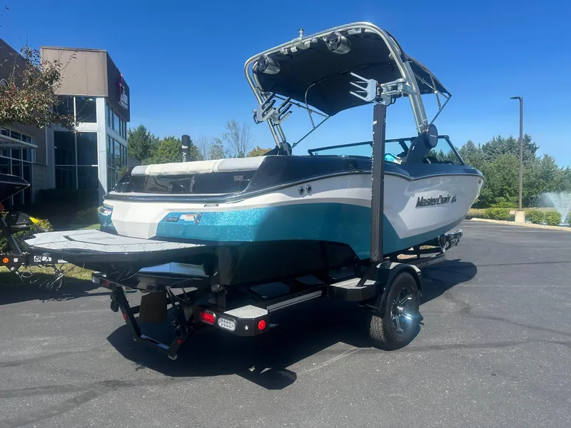 Slide: The Image of 2022 MasterCraft NXT20 boat on trailer, parked outdoors under clear blue sky. - 5
