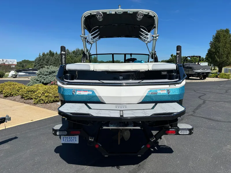 Slide: The Image of 2022 MasterCraft NXT20 boat, rear view, parked on asphalt with greenery in background. - 6