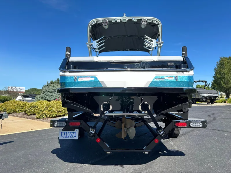 Slide: The Image of 2022 MasterCraft NXT20 boat rear view, parked on asphalt under clear blue sky. - 7