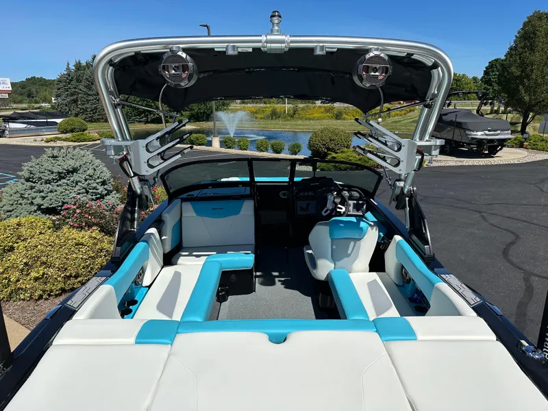Slide: The Image of 2022 MasterCraft NXT20 boat interior with blue and white seating, parked near a fountain. - 9