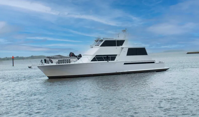 Slide: The Image of 1999 Viking 60 Cockpit Motor Yacht cruising on calm waters under a clear blue sky. - 1