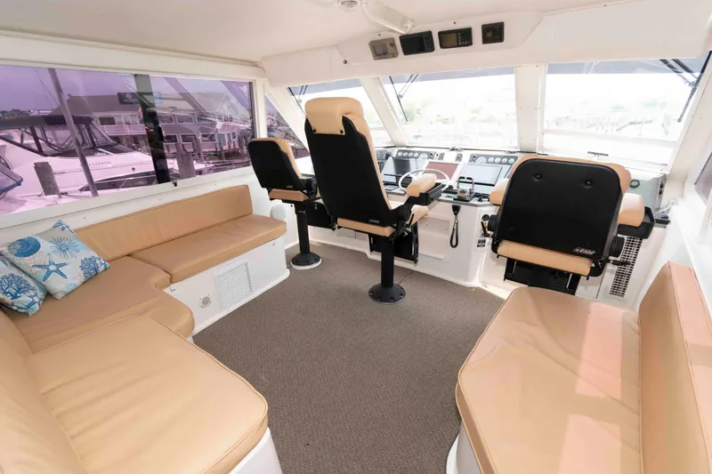 Slide: The Image of Interior of 1999 Viking 60 Cockpit Motor Yacht with beige seating and helm controls. - 13
