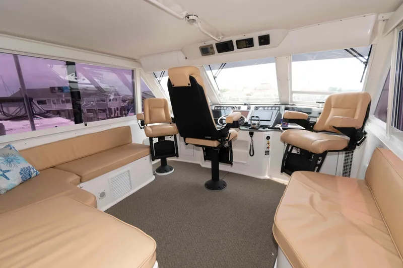 Slide: The Image of 1999 Viking 60 Cockpit Motor Yacht interior with beige seating and helm station. - 14